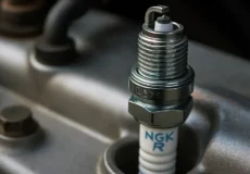 تصویر کلوزآپ شمع خودرو NGK نصب شده روی سرسیلندر موتور، بهترین مارک شمع خودرو برای عملکرد بهتر و کاهش مصرف سوخت